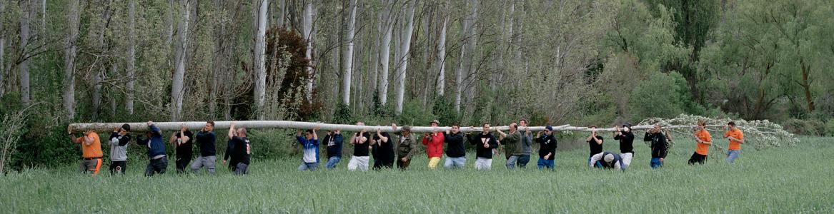 Jóvenes llevando a hombros un tronco de árbol tumbado