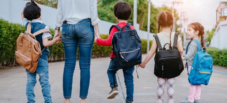 Tres niños y una madre camino de la escuela