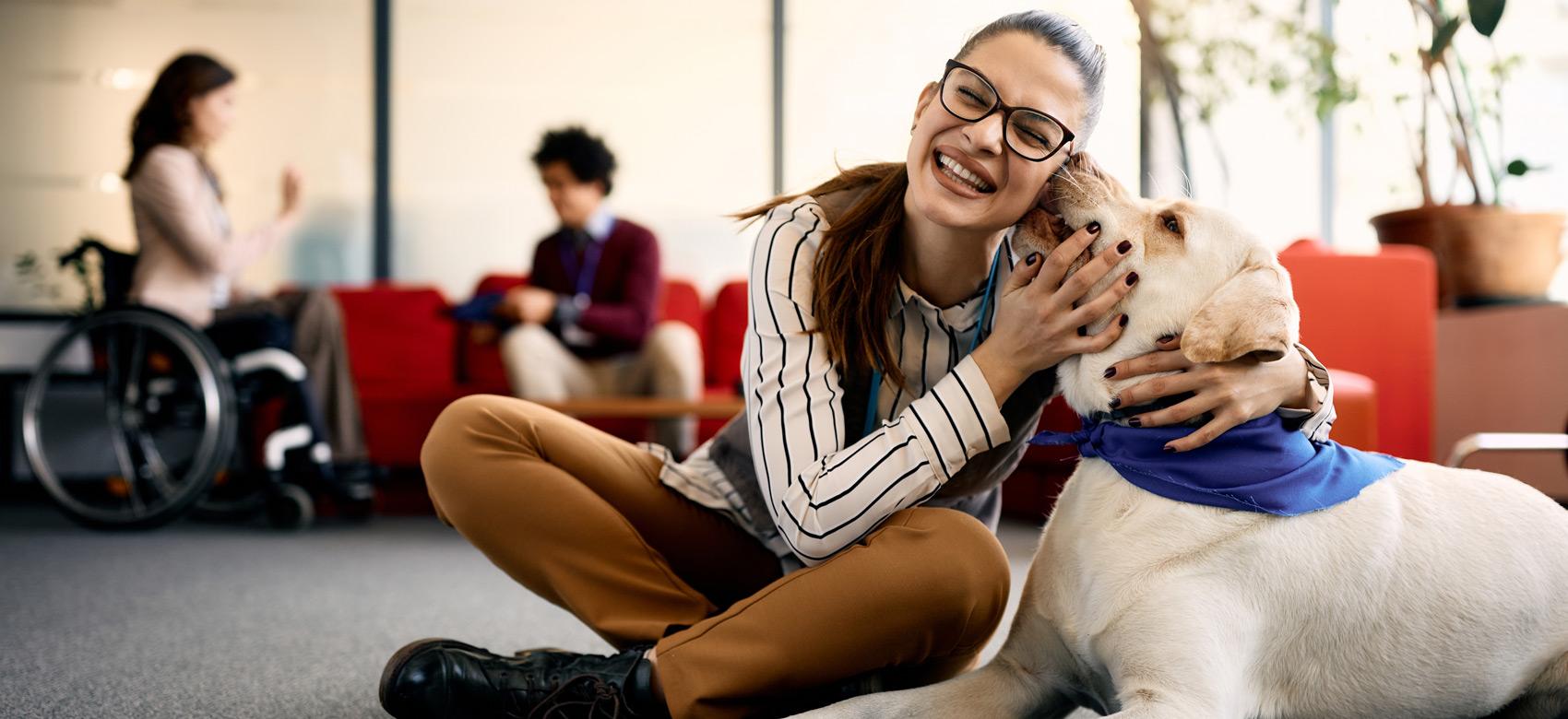 Mujer junto a perro de asistencia en una oficina