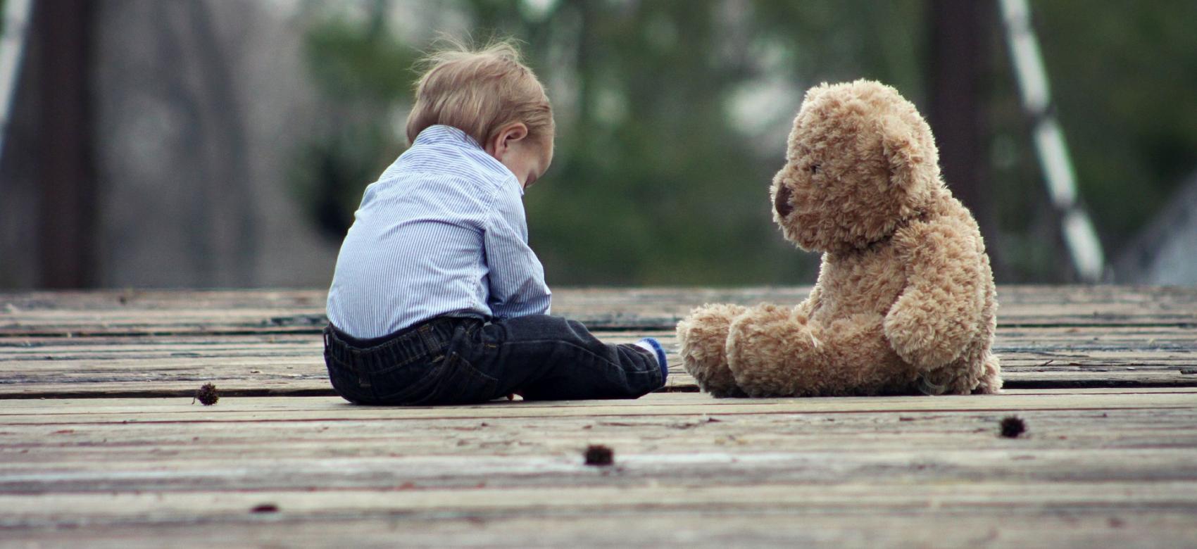 Niño jugando con un oso de peluche