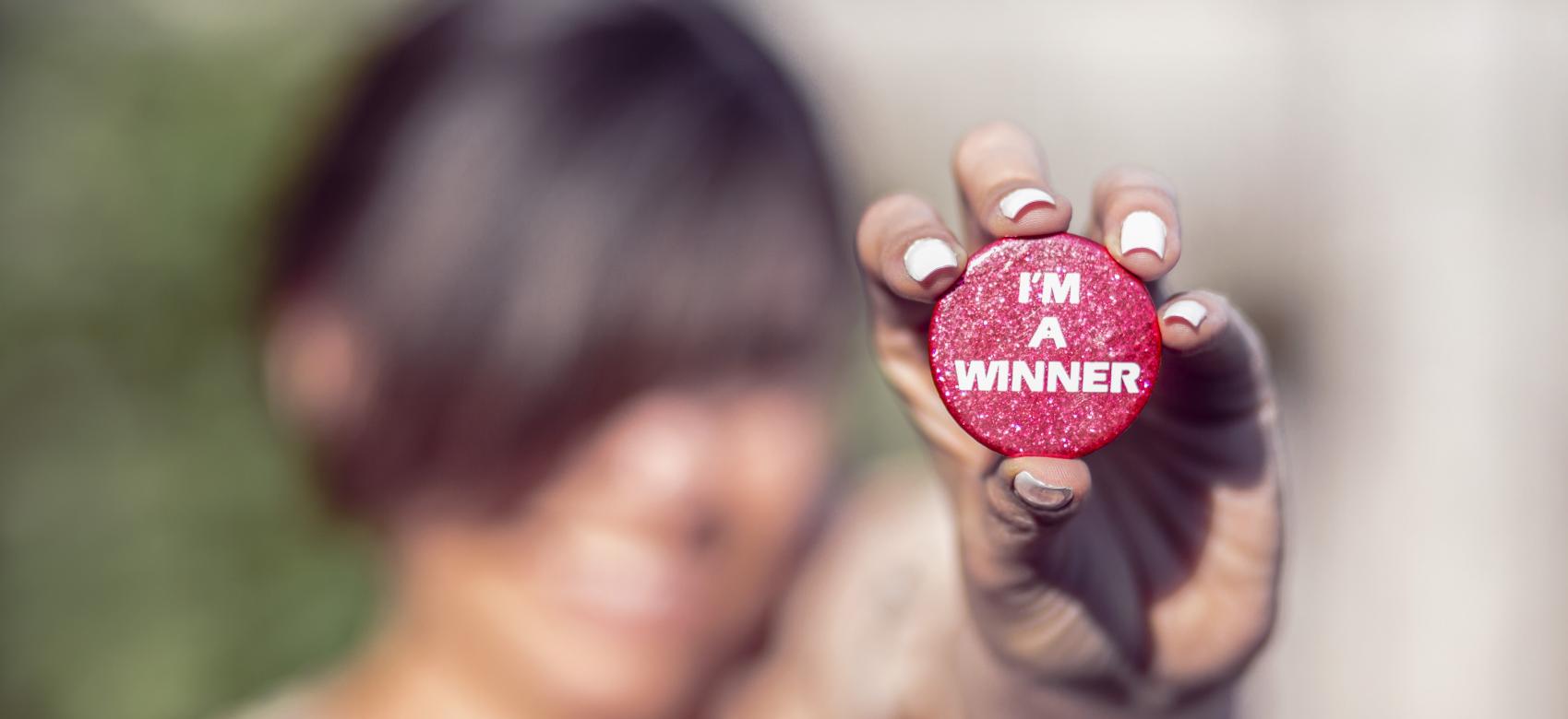 Hand holding a button with: I'm a winner