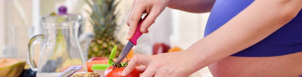 Embarazada cortando un alimento en la cocina