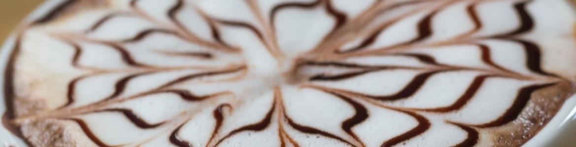 Imagen de una taza de café con espuma de leche decorada con un dibujo