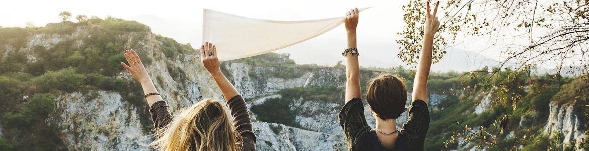 Dos chicas de brazos levantados sujetando sábana blanca