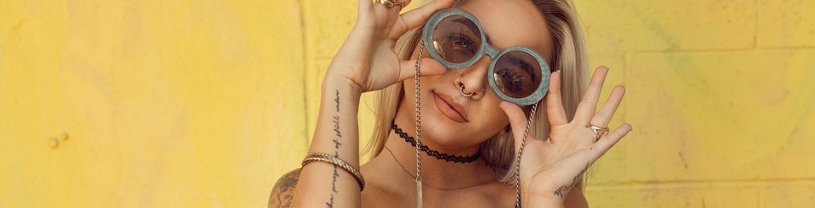 Chica con gafas amarillas y tatuajes en el brazo