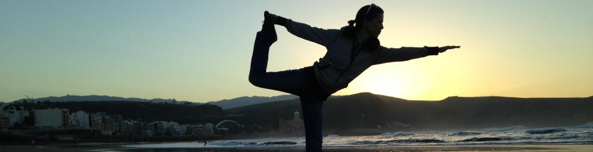 Vista de una mujer haciendo yoga en la playa