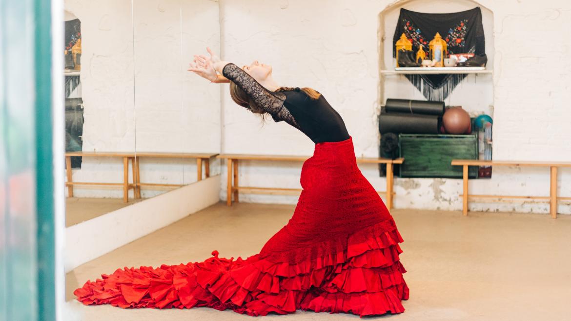 Una bailaora en su estudio con una bata de cola roja