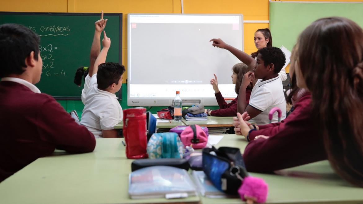 Unos niños levantan la mano en un aula de clase