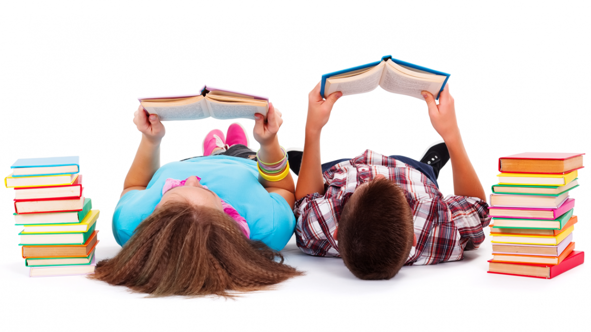 Niños tumbados en el suelo leyendo