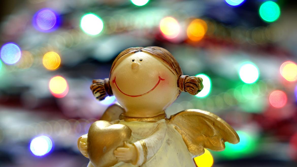 Ofrecemos actividades navideñas a pacientes y profesionales Figurita de un ángel con luces navideñas de fondo
