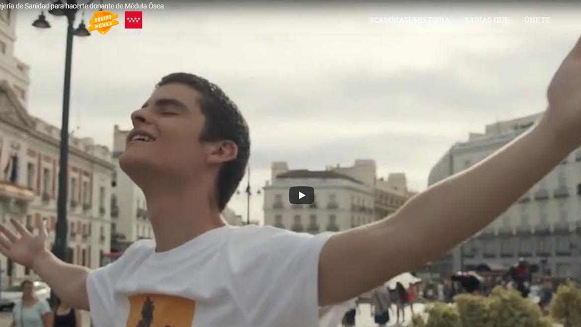 Imagen de vídeo con un joven en primer plano abriendo los brazos y mirando al cielo en la Puerta del Sol 