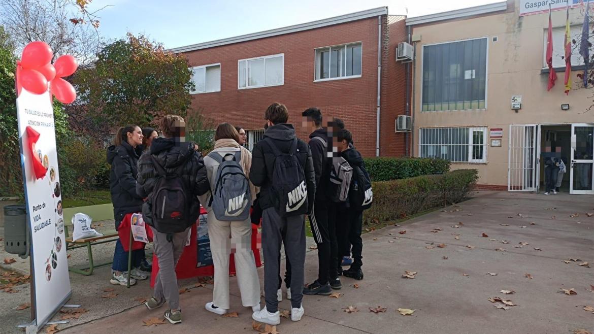 jovenes en la entrada de su instituto en una mesa informativa del centro de salud