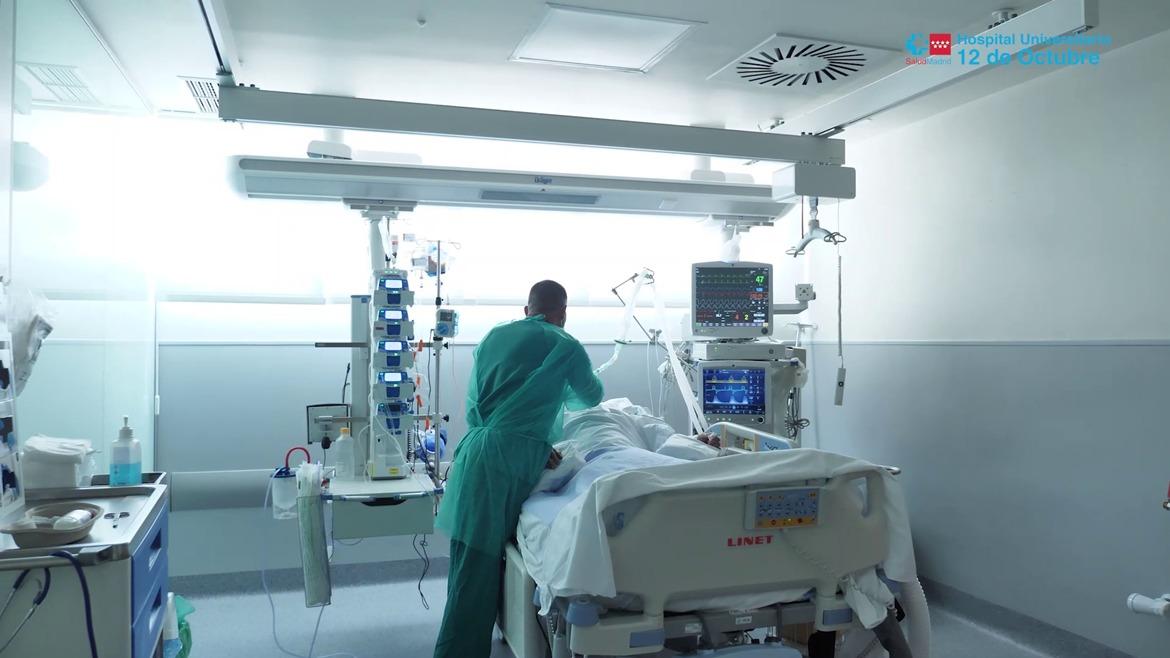 Un médico al fondo sobre una camilla