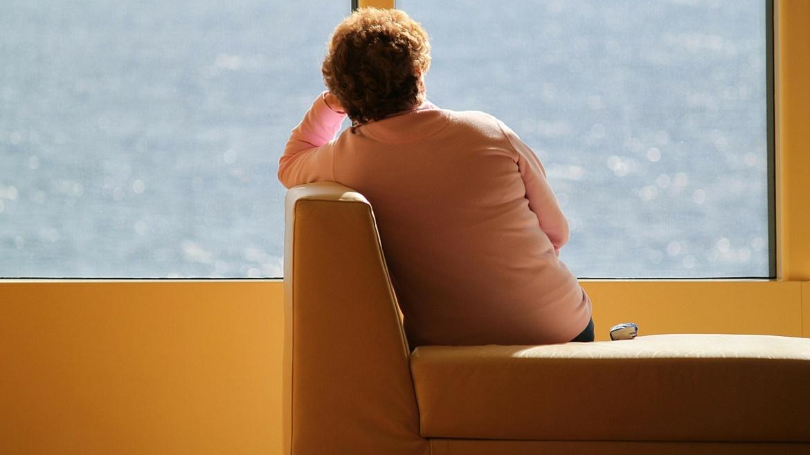 Mujer sentada mirando al infinito por un ventanal Mujer sentada mirando al infinito por un ventanal