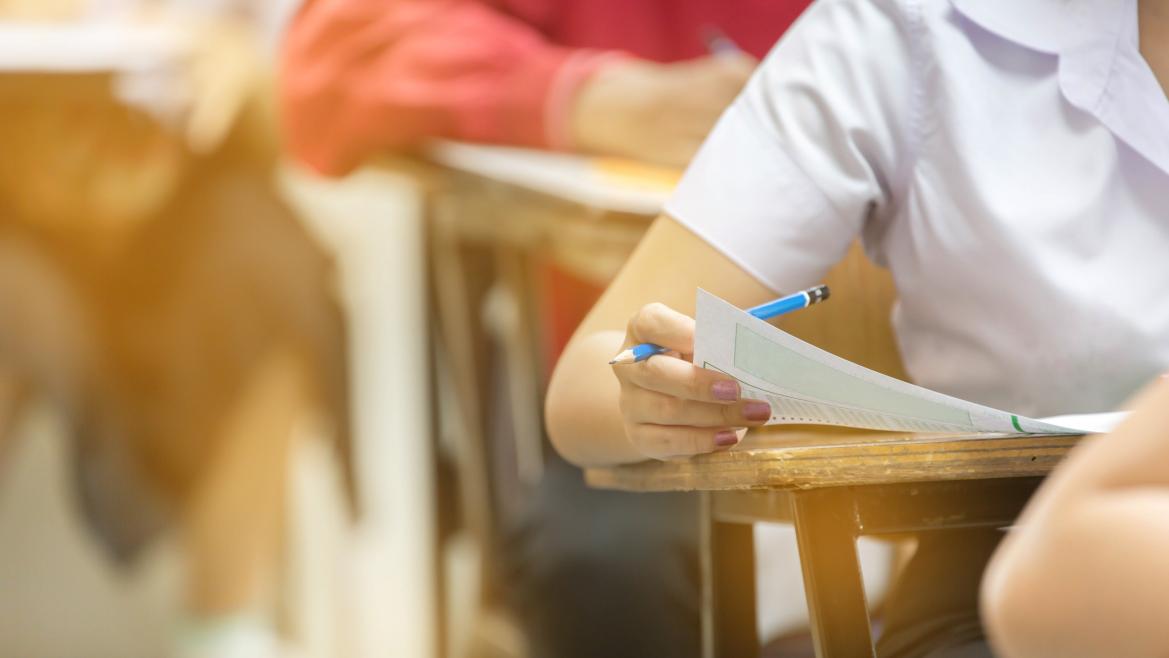Unos alumnos escribiendo en un pupitre
