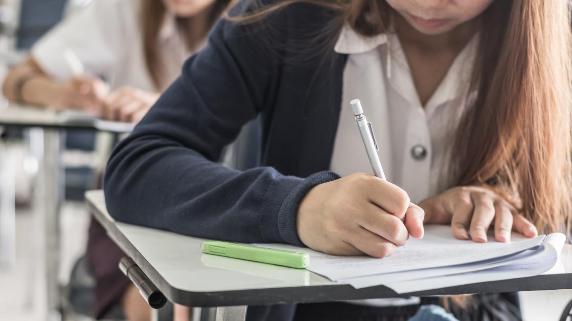 Una niña escribe en su pupitre