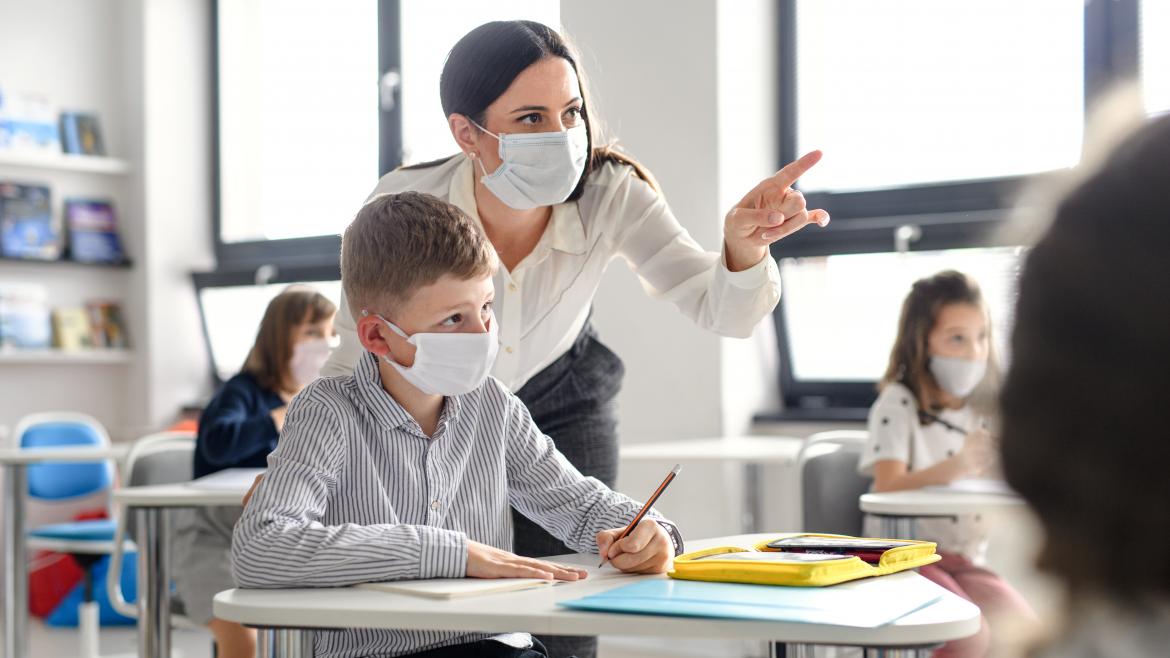 Una maestra explica a un alumno algo que observan en la pizarra