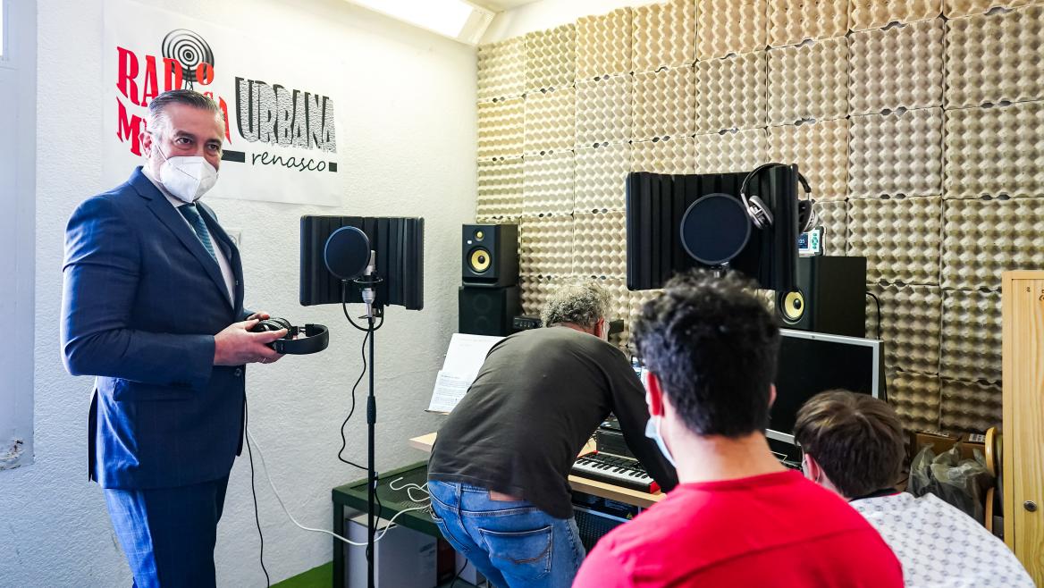 El consejero durante la actividad de radio frente a un micrófono y a un grupo de jóvenes