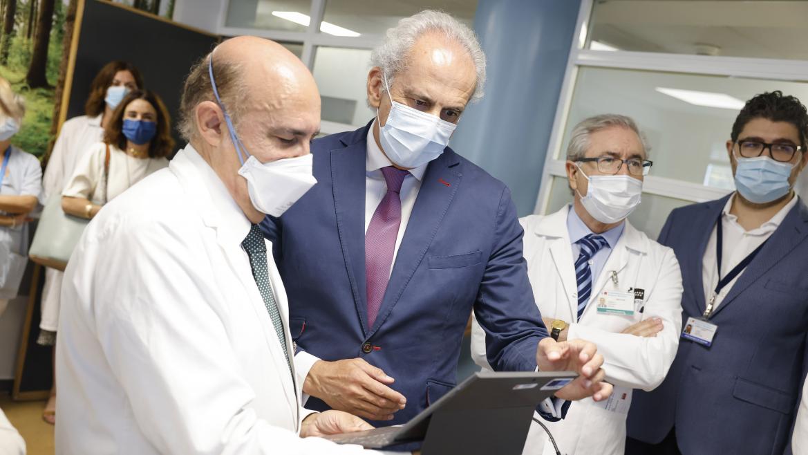 El consejero Enrique Ruiz Escudero observa una tablet mientras habla con un médico
