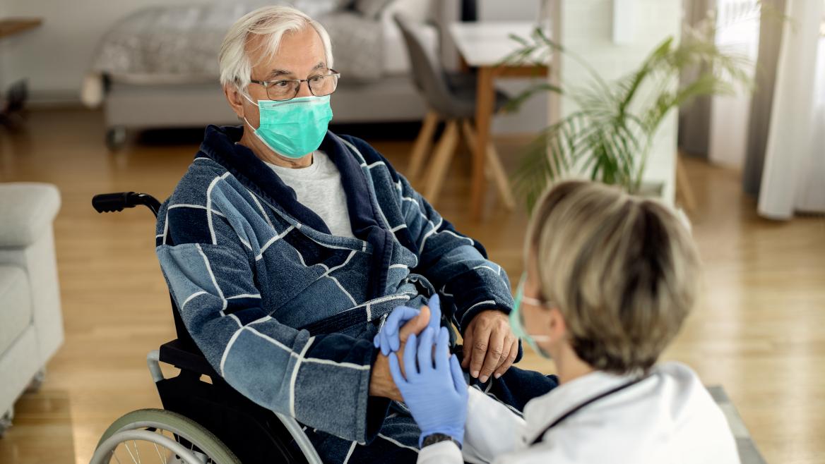 Persona mayor en silla de ruedas junto a una médico