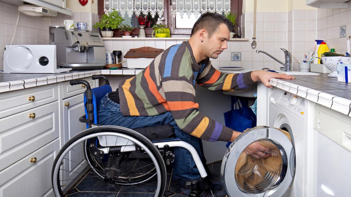 Joven con discapacidad física poniendo la lavadora