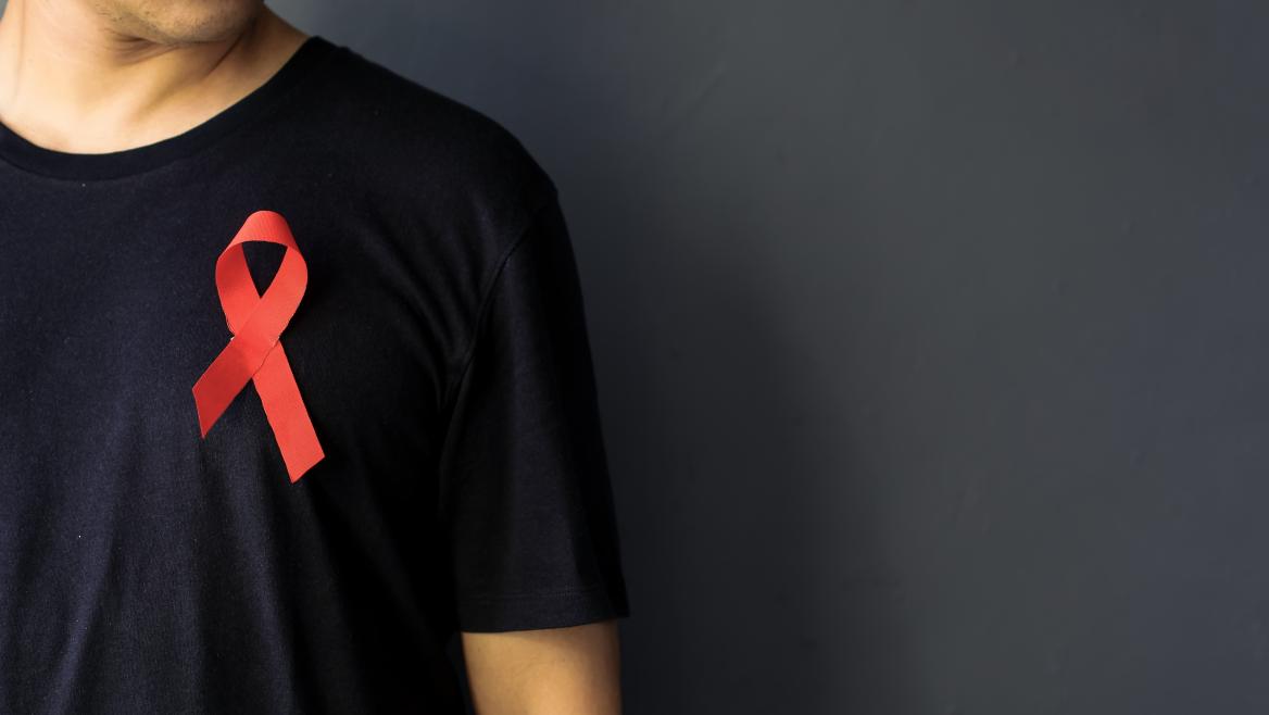 Hombre con camiseta negra con un lazo rojo