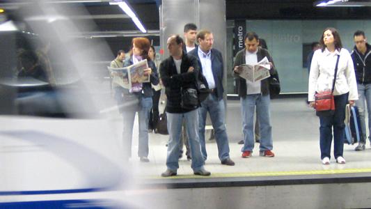 Personas esperando en andén mientras el metro entra en la estación