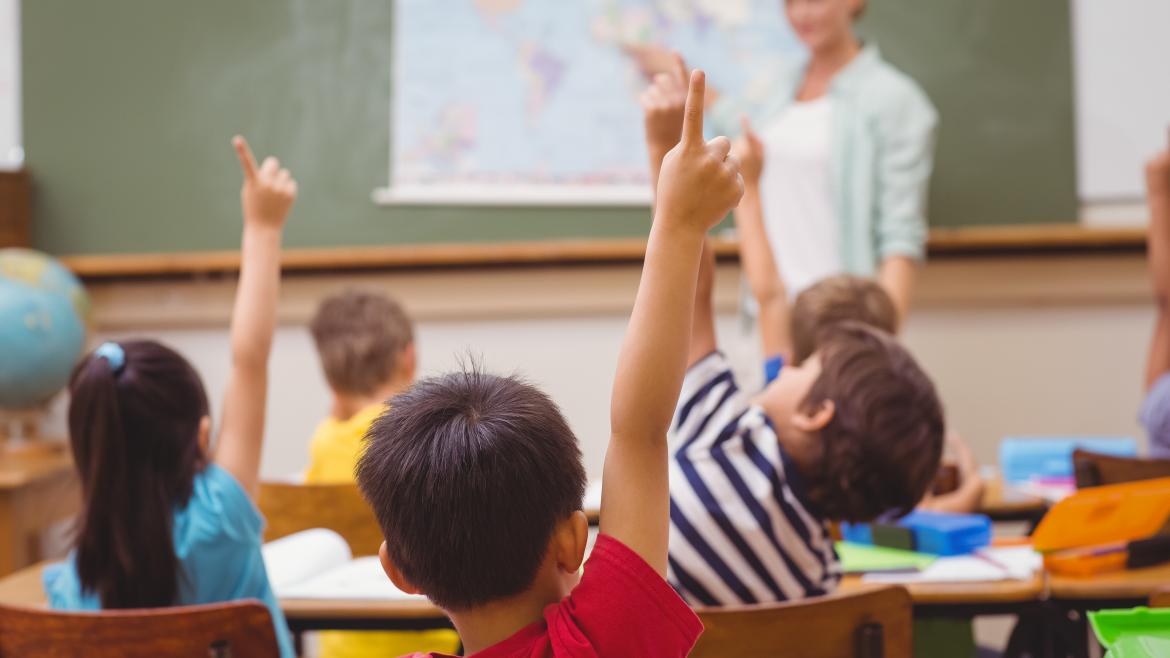 Unos niños levantan la mano durante una clase