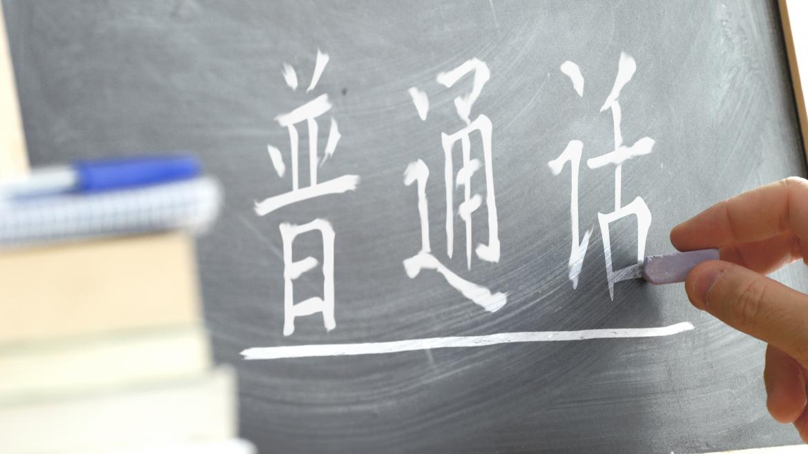 Una mano escribiendo las palabras "chino mandarín" en chino