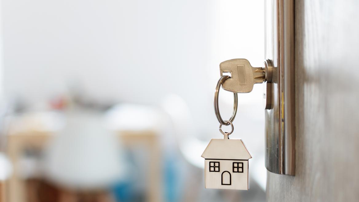 Llave colgando de una puerta con un llavero de una casa