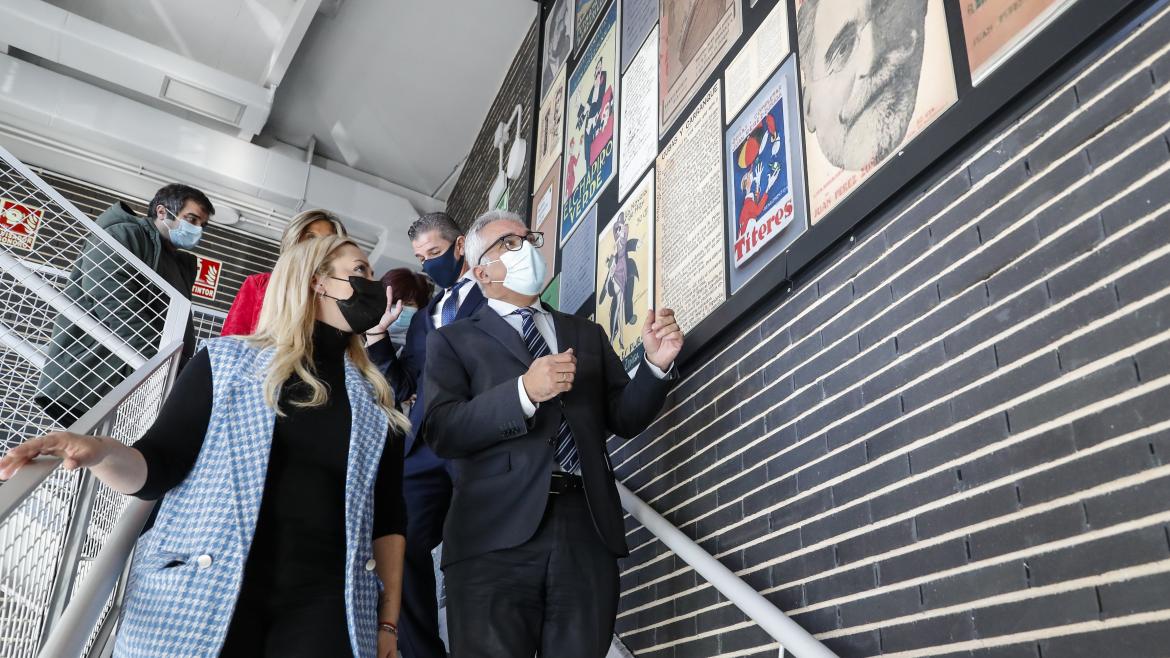 El consejero bajando las escaleras del centro y contemplando una pared con carteles cinematrográficos