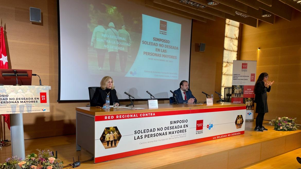 La consejera interviniendo sentada en la mesa del acto en el escenario