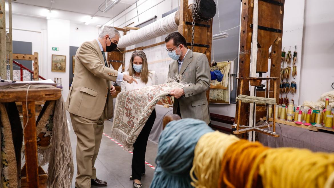 El consejero junto con trabajadores de la fábrica de tapices mirando una alfombra