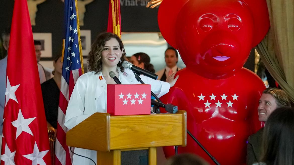 Isabel Díaz Ayuso hablando desde atril con escultura de un oso