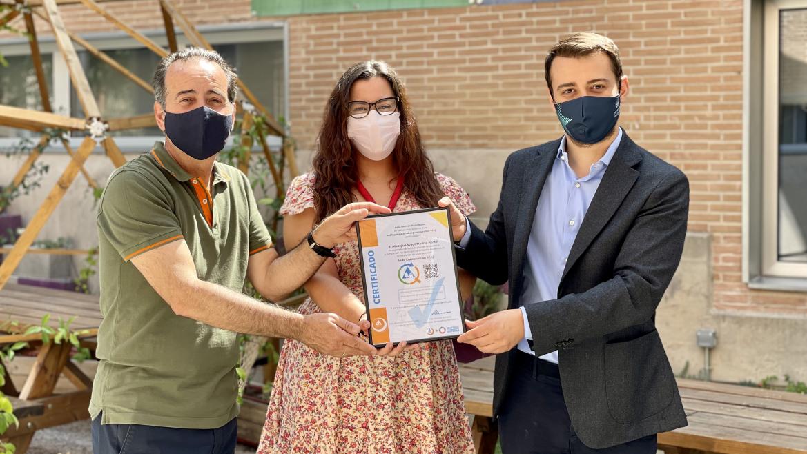 El Director General de Juventud sostiene junto con otro hombre y una mujer un marco con un certificado medioambiental 