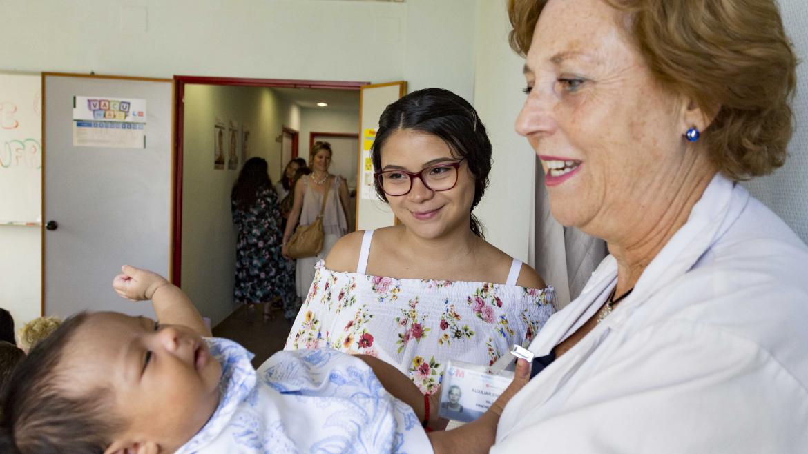 Una matrona sostiene un bebé mientras su madre mira sonriente