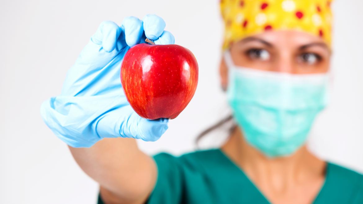 Un profesional sanitario con una manzana en la mano