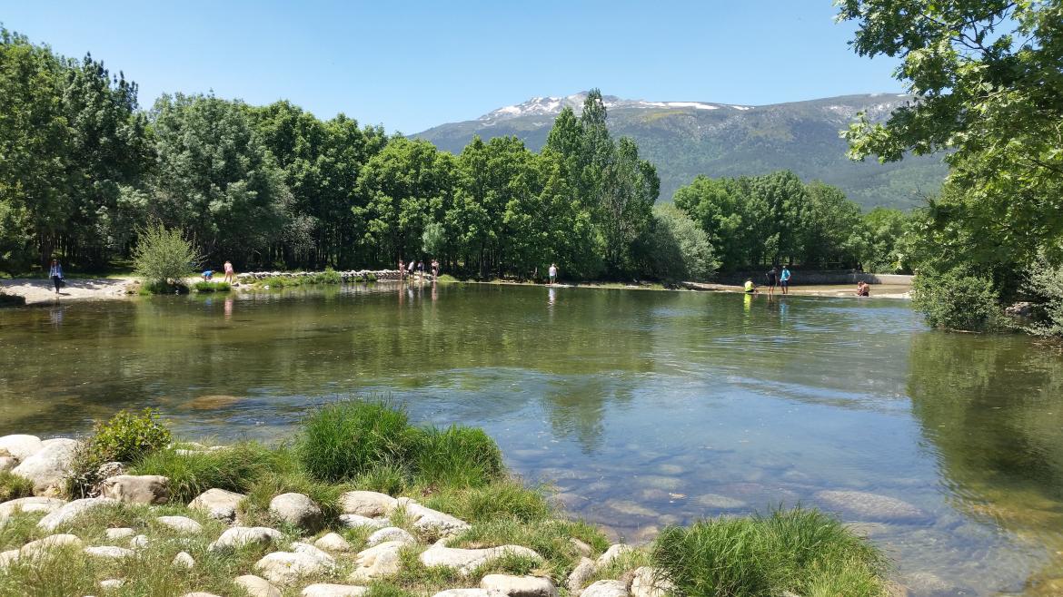 Piscina natural de la sierra de Madrid con bañistas al fondo