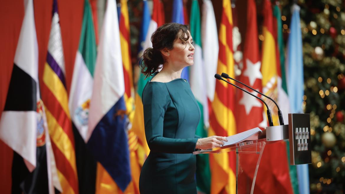 La presidenta con un vestido verde delante de las banderas en el acto