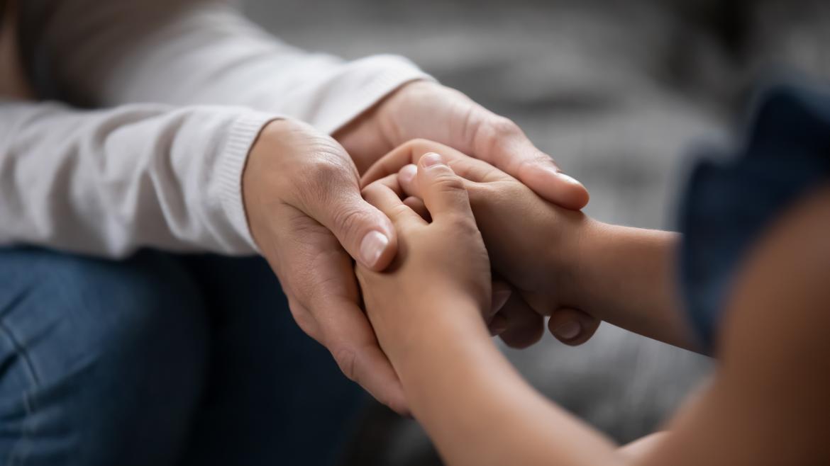 Las manos de una persona mayor tomando las de un niño