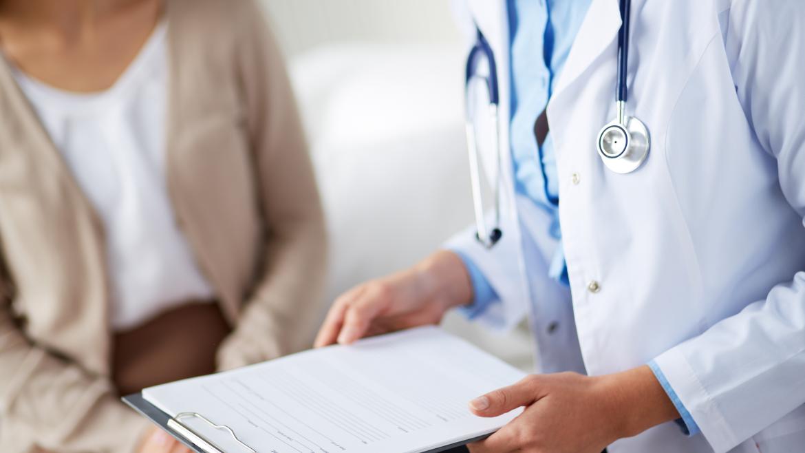 Las manos de un doctor con una carpeta conversando con un paciente