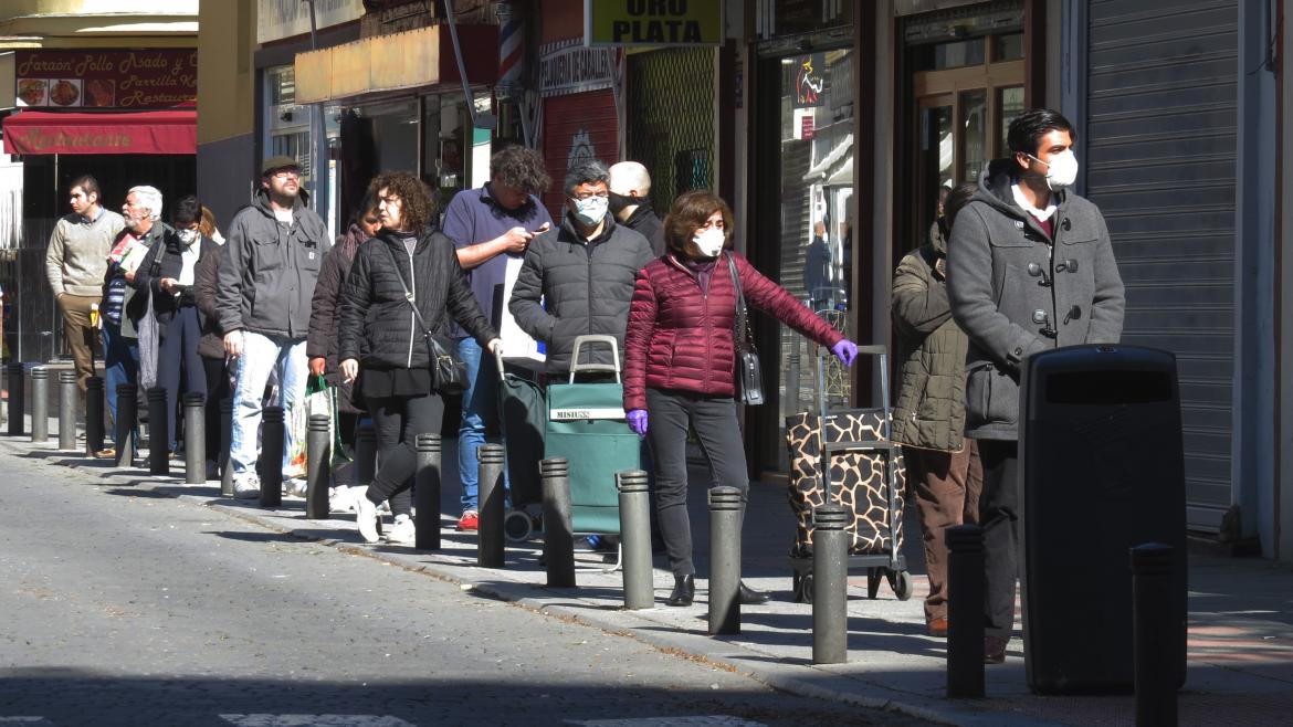 Un grupo de personas con maletas hacen una fila