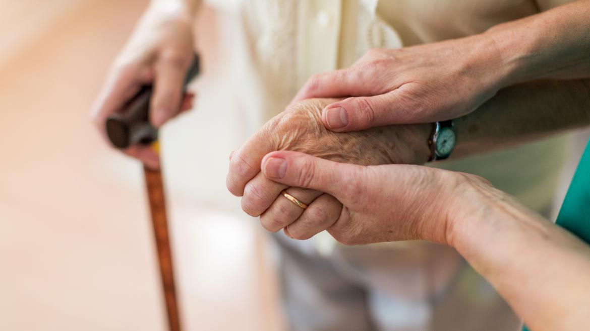Las manos de una cuidadora cogiendo la mano de una señora mayor