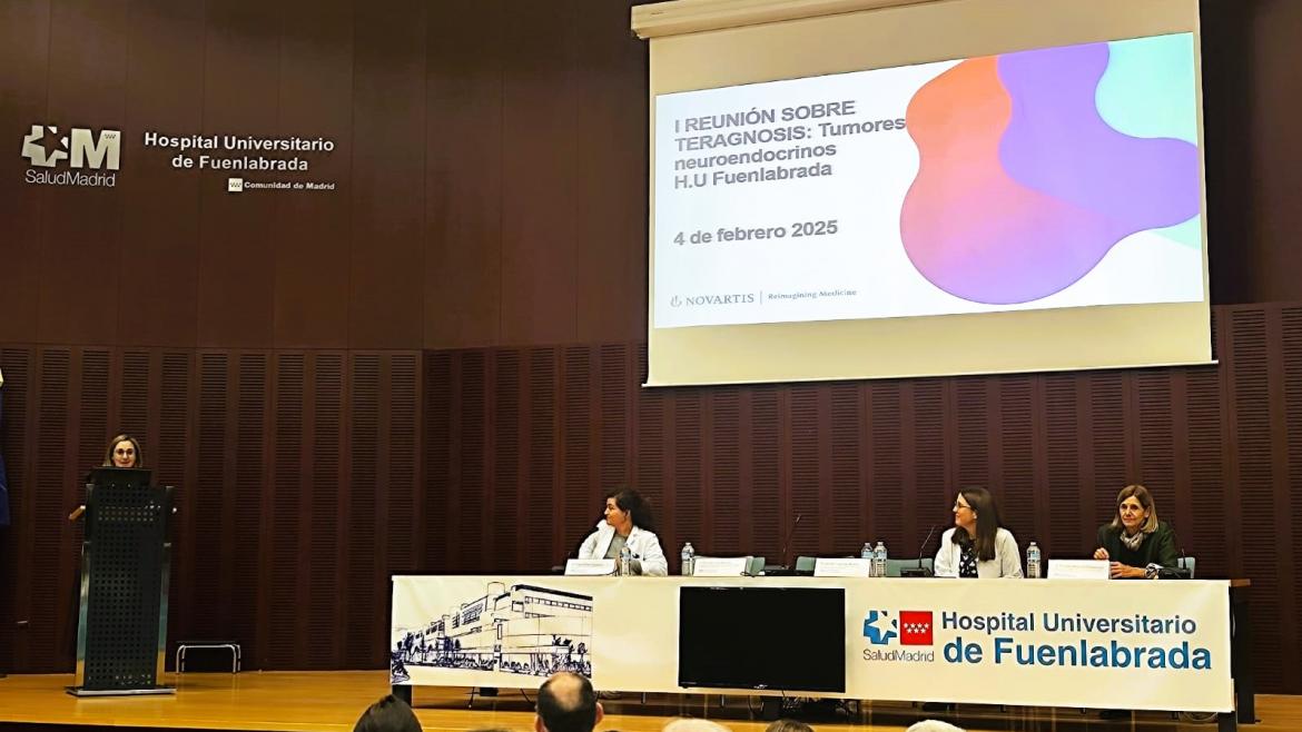Personas sentadas en una mesa dentro de un auditorio