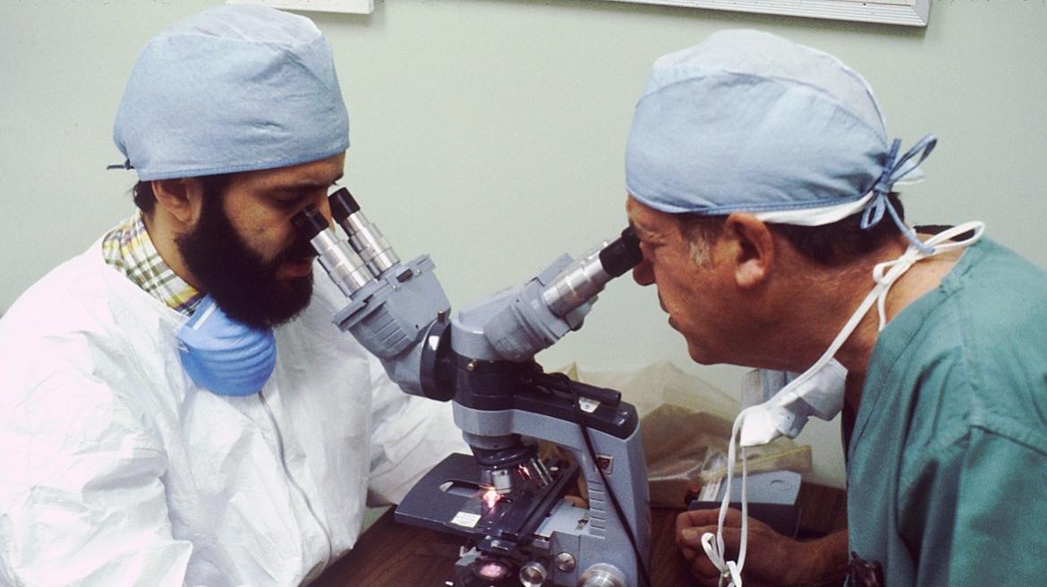 Dos médicos miran por dos visores del mismo microscopio