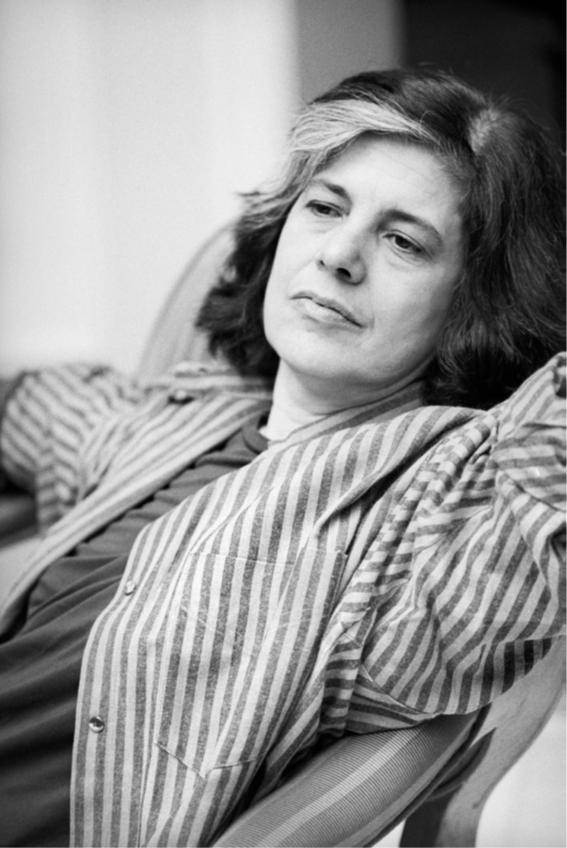 Retrato de una mujer escritora sentada, mirando al horizonte y con una camisa de rayas