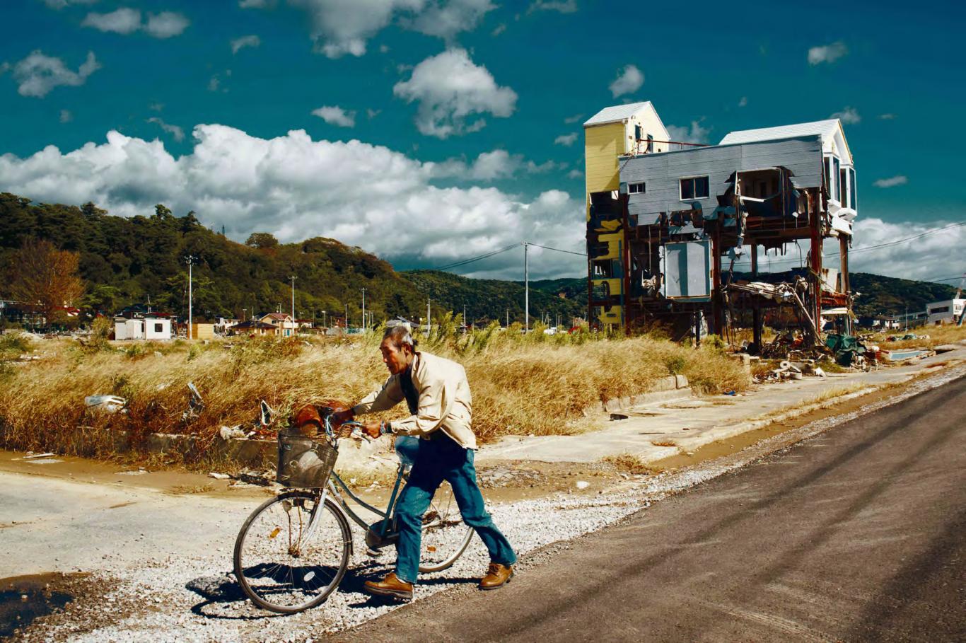 Escena de una ciudad desolada con un hombre caminando, bicicleta en mano, entre la soledad