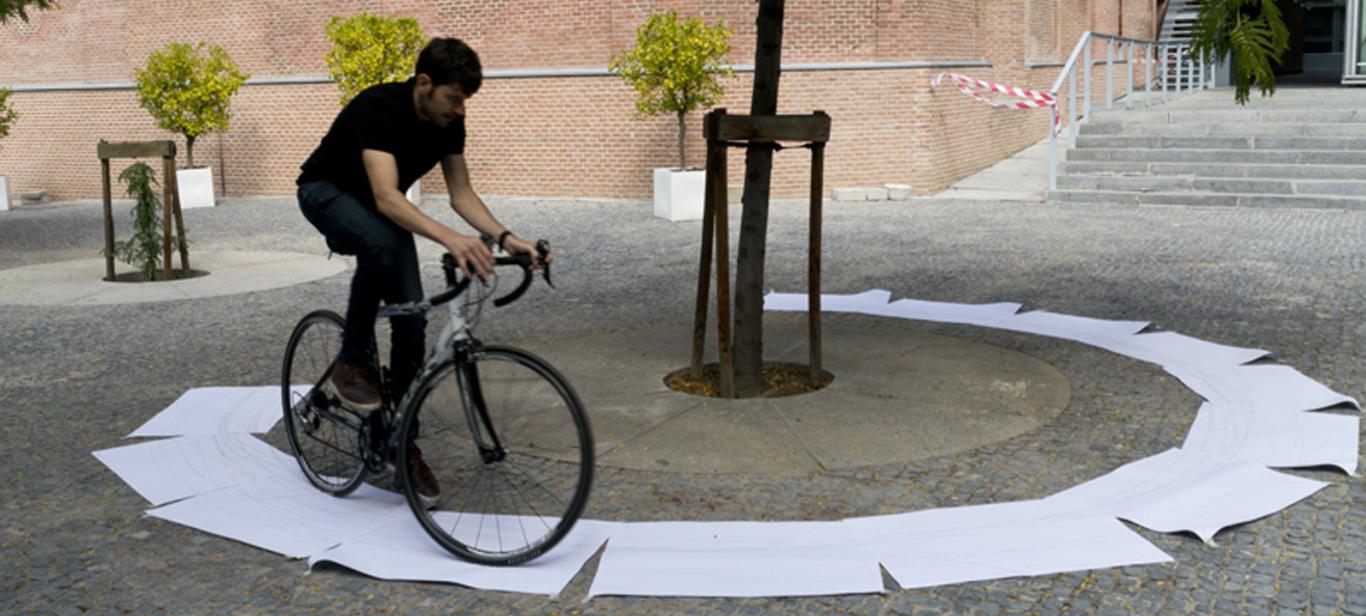 Joven montando en bicicleta sobre un círculo hecho con papeles blancos