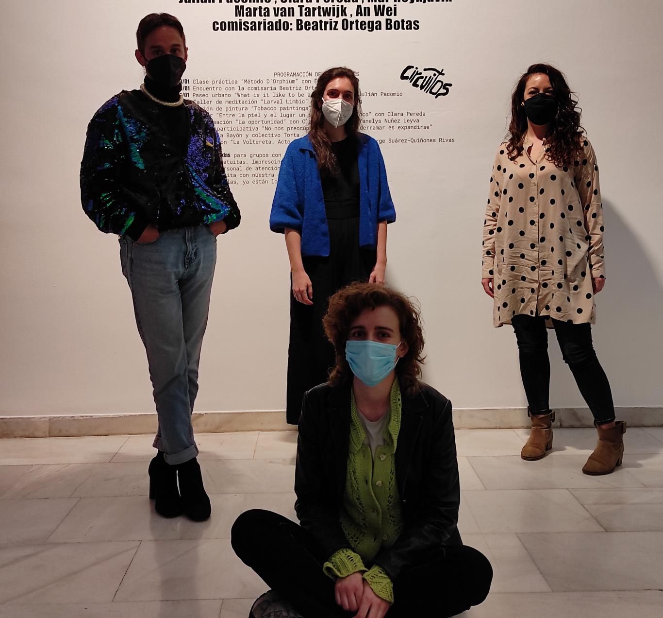 4 people posing in front of a young art room wall