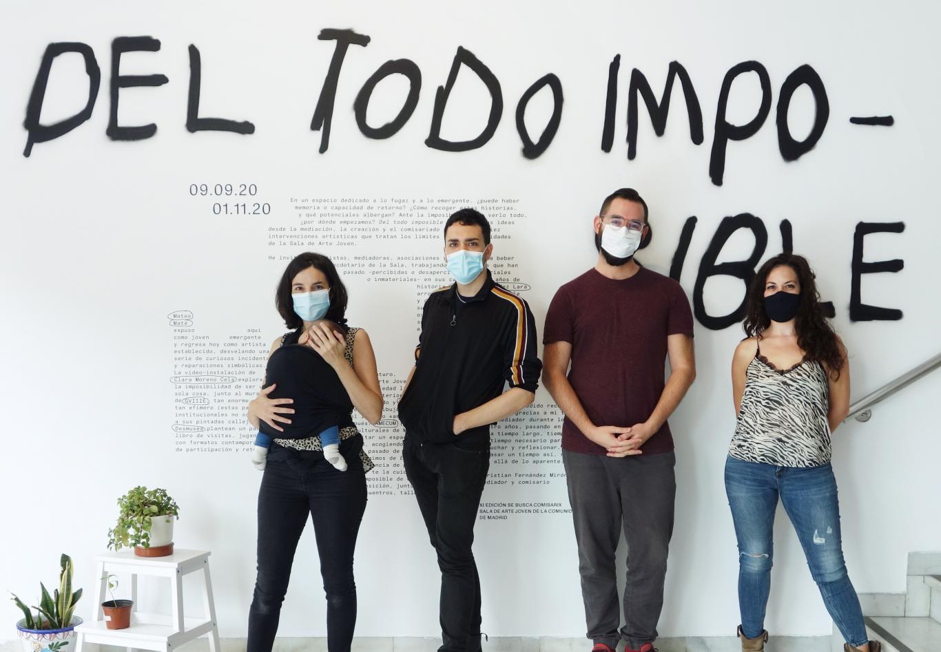 Cuatro jovenes posan frente a un muro con un grafiti donde se lee Del todo imposible